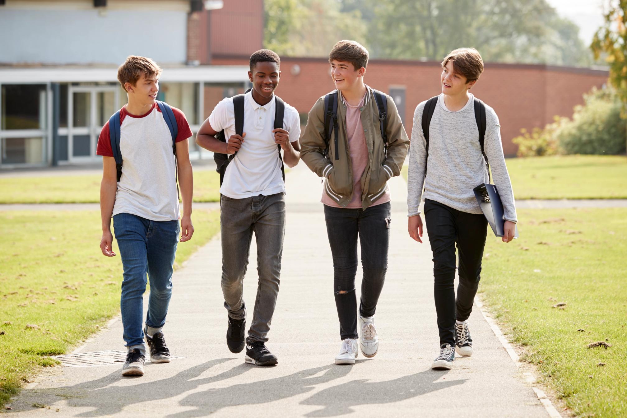 Happy teenage boys walking together on a school campus.