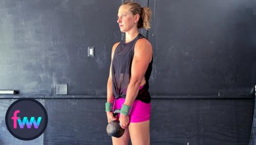 Kindal at the bottom of the kettlebell curl with her arms extended down.