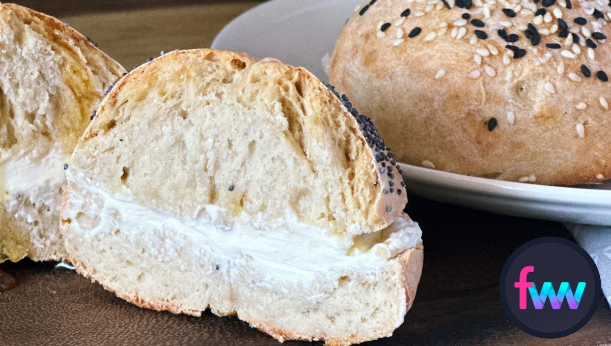 A bagel sliced open dripping with warm cream cheese.
