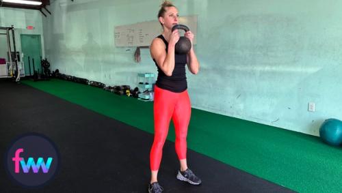 Kindal at the top of the kettlebell goblet squat holding the kettlebell with two hands.