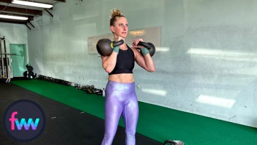 Kindal at the bottom of double presses standing tall and bracing to push the kettlebells over her head.