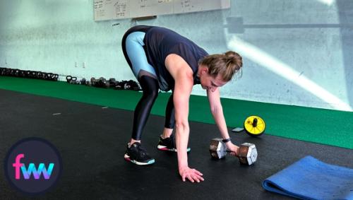 Kindal is in the tucked position of the burpee snatch and notice her hand remains on the dumbbell handle.