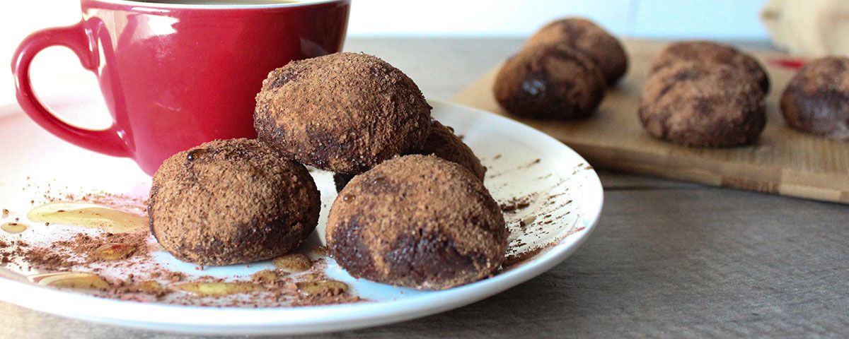 Cinnamon Donut Holes Four chocolate dusted cinnamon donut holes next to a cup of coffee