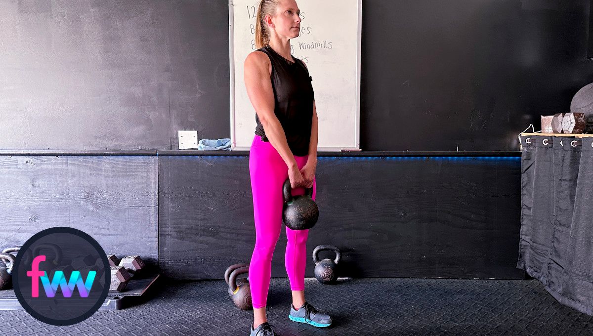 Kindal at the top of the kettlebell deadlift with her shoulders pulled back and her body is fully engaged.