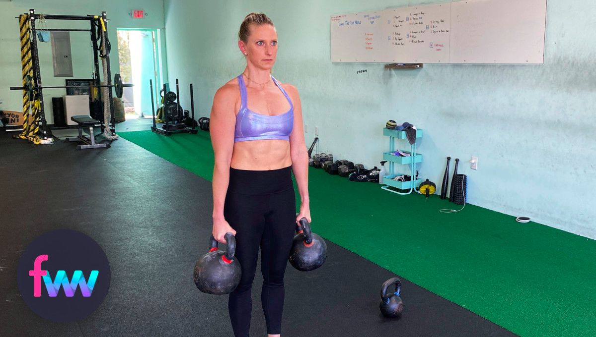 Kindal holding two HEAVY kettlebells in farmers carry.