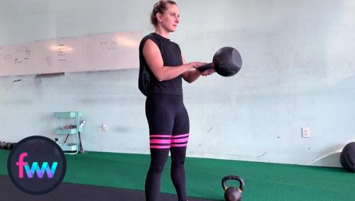 Kindal at the top of the kettlebell swing. Her arms are packed and the kettlebell is at chest height. She if fully locked out in her legs and balanced.