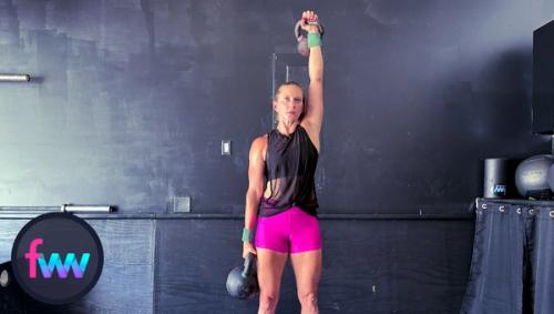 Kindal at the top of the press. Her body is tight to support the farmers carry but also to press the kettlebell over her head.