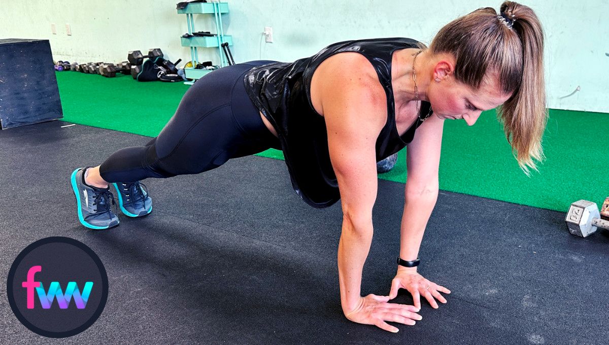 Kindal at the top of diamond pushups with her shoulders over and slightly past her hands. Her body is straight and fully engaged.