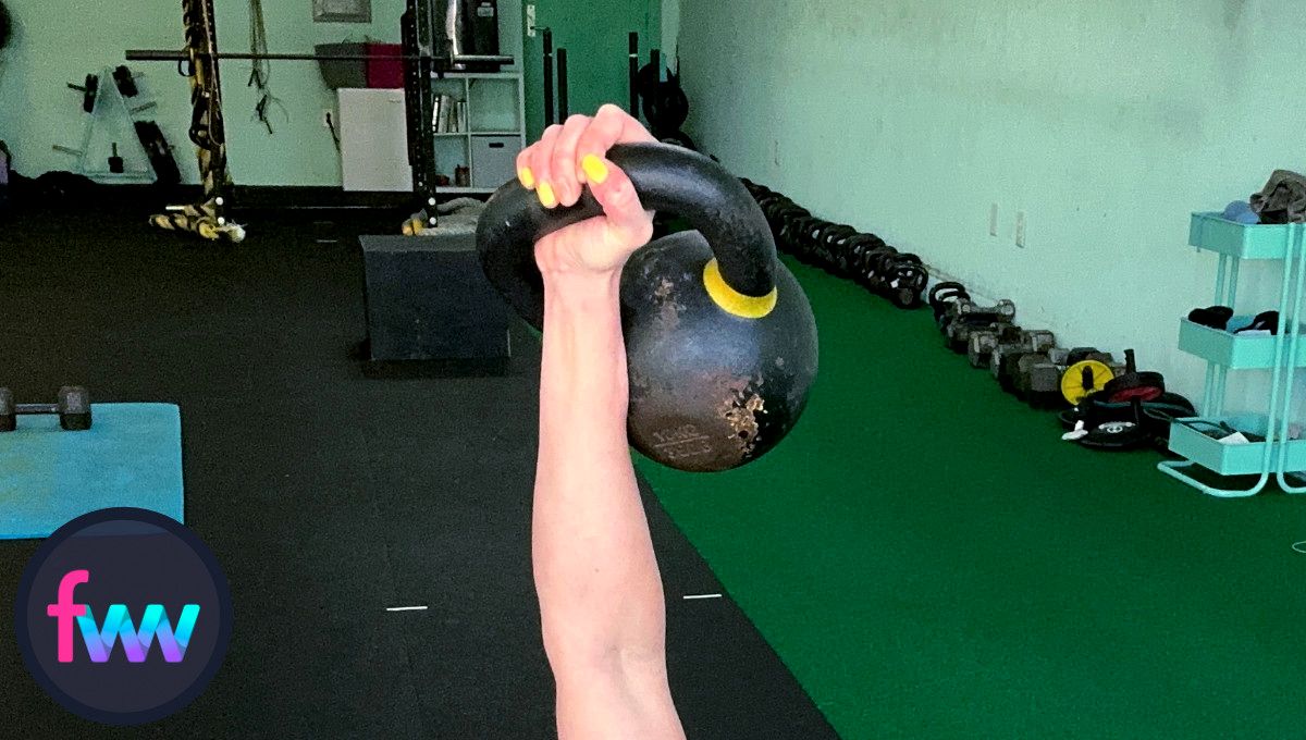 Kindal holding up a kettlebell and you can see how the bulk of the weight is off to the side. This creates the offset center of gravity that make kettlebells so effective for full body workouts.