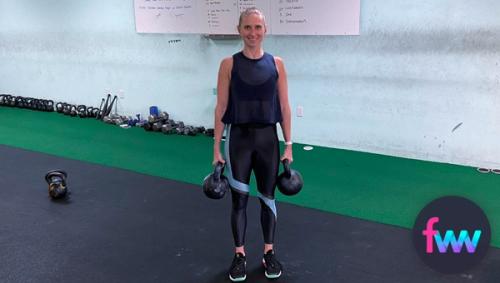 Kindal holding two kettlebells suitcase style.