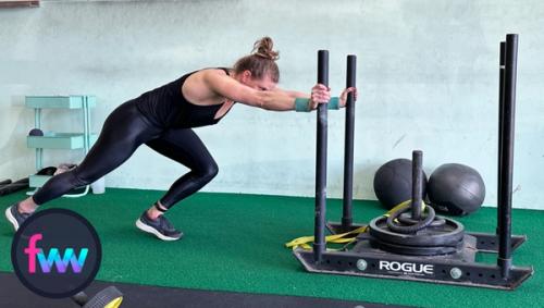 Kindal pushing the sled with straight arms driving her legs hard.