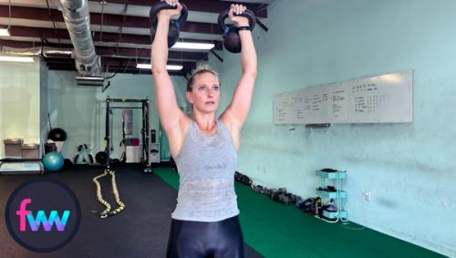 Kindal at the top of the double kettlebell presses. You should try to get your arms strength. You can see how Kindal lacks some shoulder mobility.