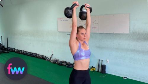 Kindal holding two kettlebells over her head.