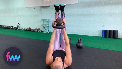 Kindal at the start of single kettlebell toe touches.