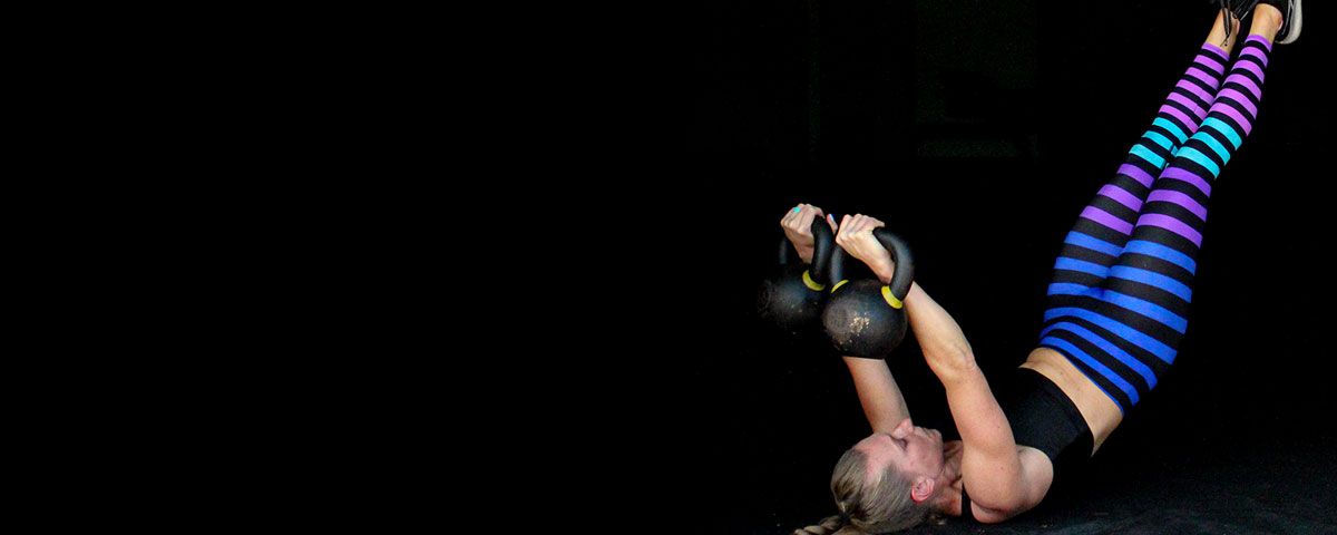 Double Trouble Kettlebell Program Kindal doing a very difficult double kettlebell scorpion ab exercise