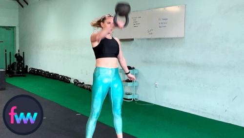 Kindal in the middle of punching through the kettlebell as she gets it up over her head.