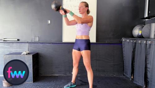 Kindal at the top of the kettlebell swing with her arms swinging out from her shoulders and her body locked out while maintaining her balance.