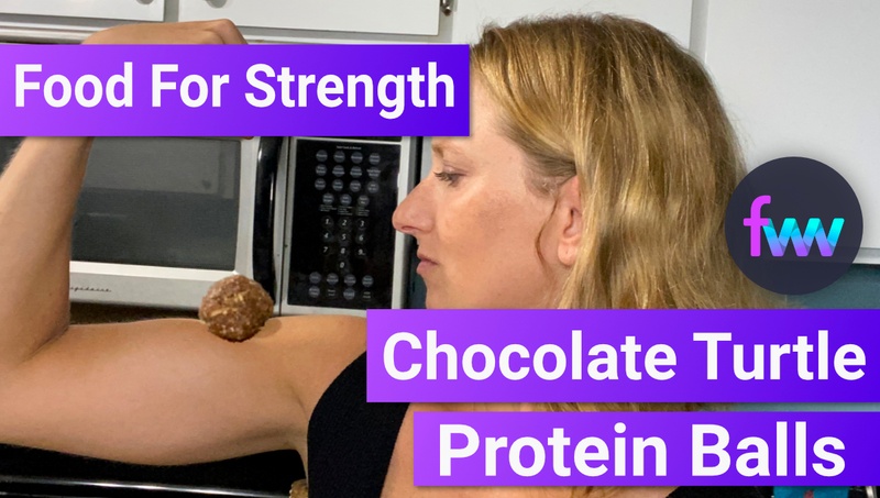 Kindal flexing with a chocolate protein ball on her bicep.