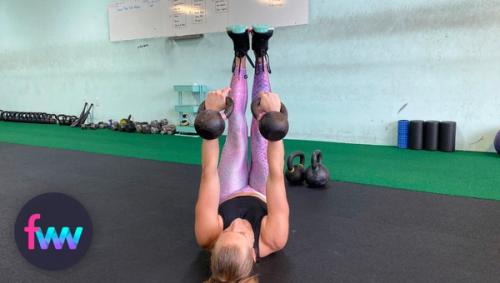 Kindal at the top start position of the double kettlebell toe touch.