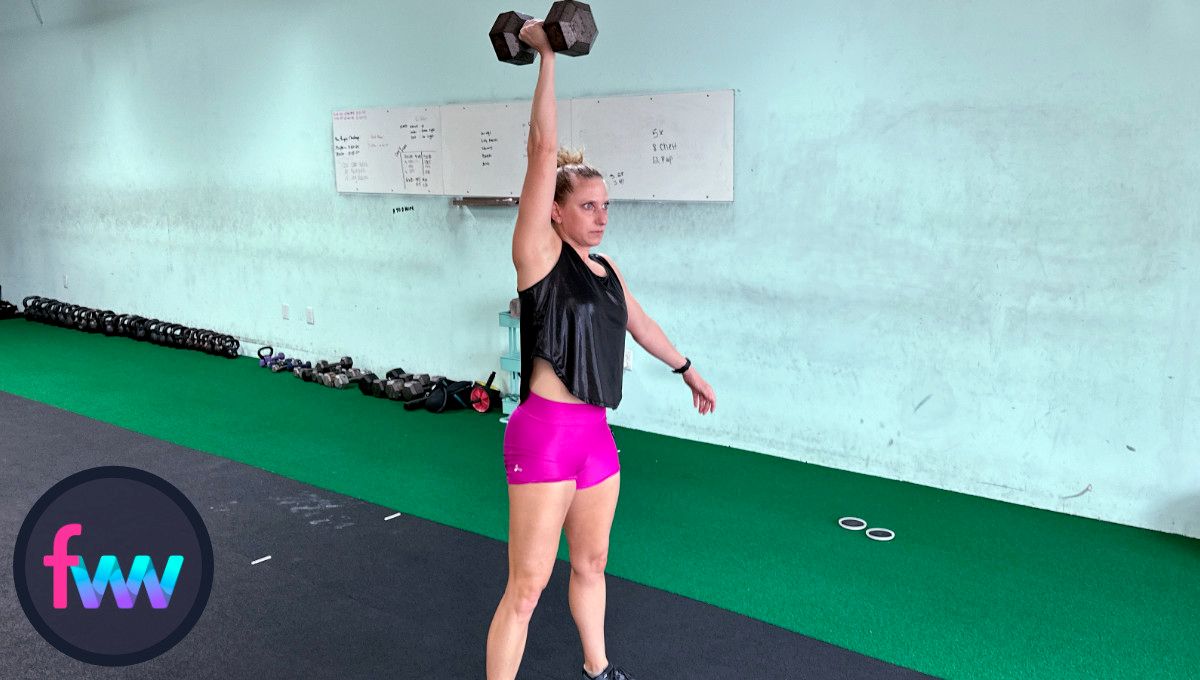 Kindal fully extending the dumbbell over her head and still maintaining good balance through her feet.