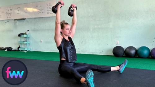 Kindal presses her legs into the ground and at the same time she presses the weights to the sky so she can sit up all the way.