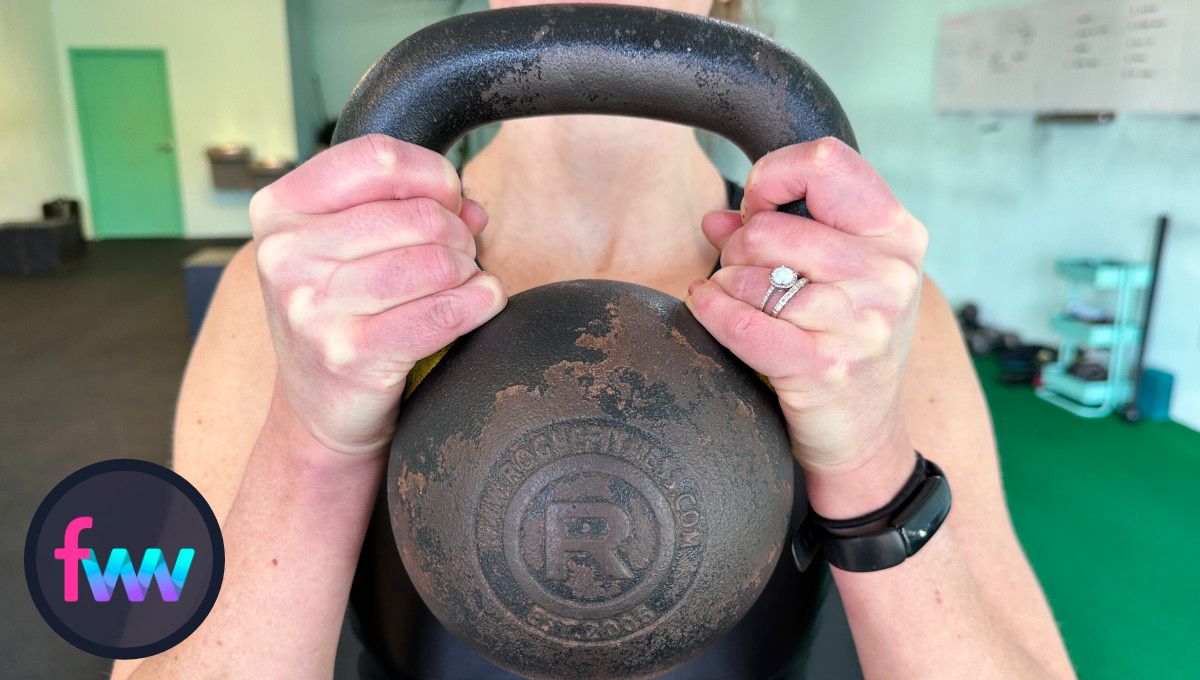 Kindal showing how to hold the kettlebell for the goblet squat. Hold the bell directly under the handles.
