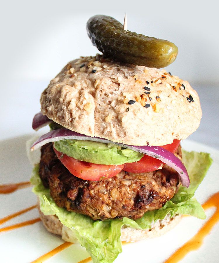 A vegetarian lentil burger with crispy lettuce and avocado