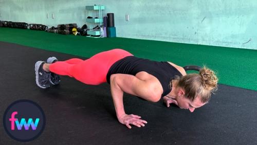 Kindal at the bottom of her pushup with her elbows in tight and her body is in one straight line.