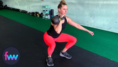 Kindal at the bottom of the racked kettlebell squats fully engaged and ready to move with a quick pace.