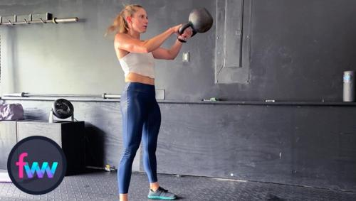 Kindal at the top of the kettlebell swing locked out and focused on squeezing her butt with maximum glute activation.