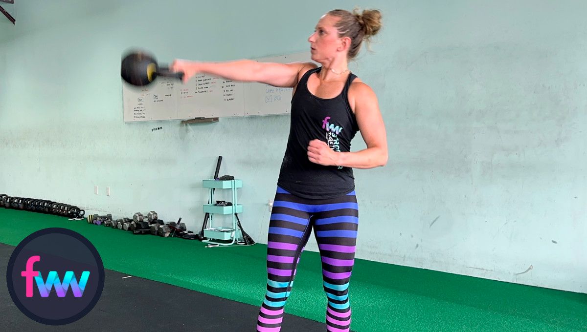 Kindal at the top of the lateral kettlebell swing with the kettlebell just above her chest height and her body fully engaged.