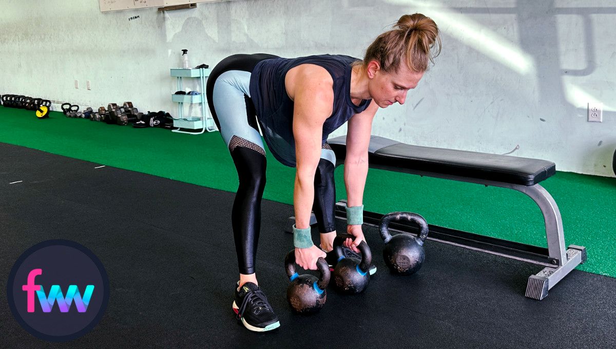 Kindal at the bottom of the double kettlebell rows. Notice her wide stance and her spine is parallel to the floor. Kettlebells are between her feet.