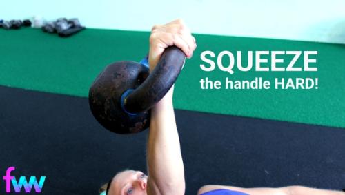 Kindal squeezing the handle of her kettlebell.