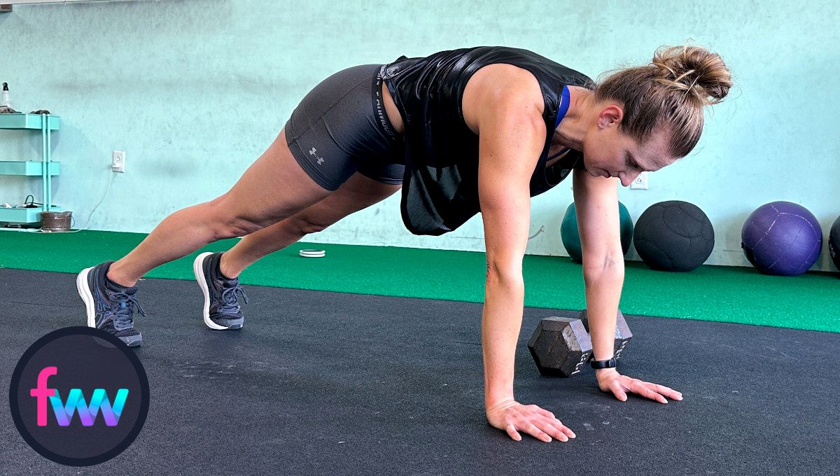 Kindal at the beginning of the dumbbell plank pull throughs with the weight outside of her hand. Her plank position is very strong and her body is in a straight line.
