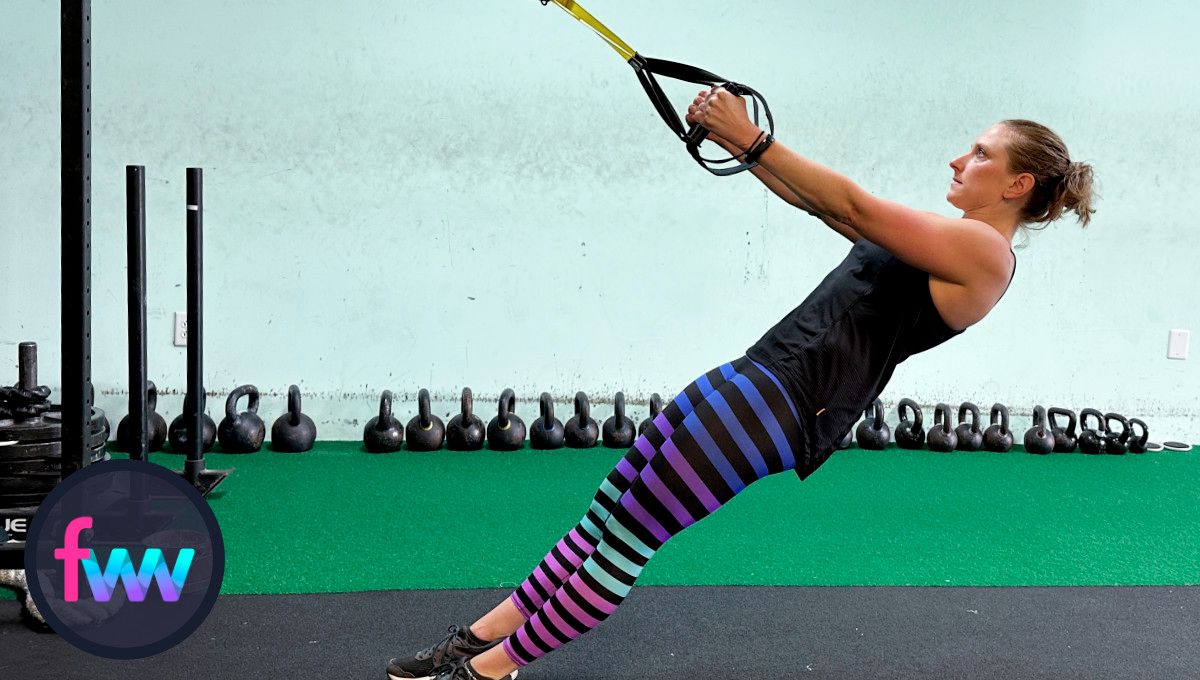 Kindal at the bottom of the TRX row with her arms fully extended but her body is straight and fully engaged.