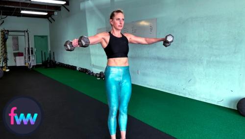 Kindal at the top of the lateral raises with dumbbells and notice how her thumbs are slightly higher than her pinkies putting her shoulders into a good position.