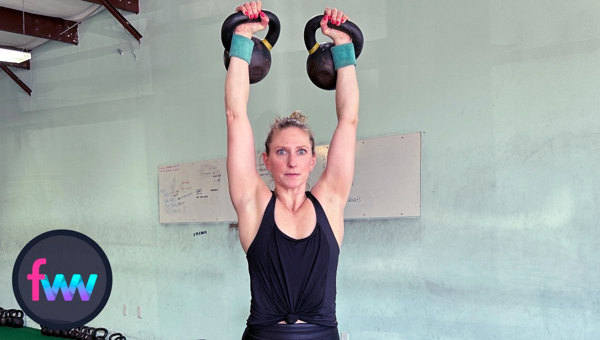 Kindal fully pressing the kettlebells over her head while maintaining an engaged body for balance and posture.