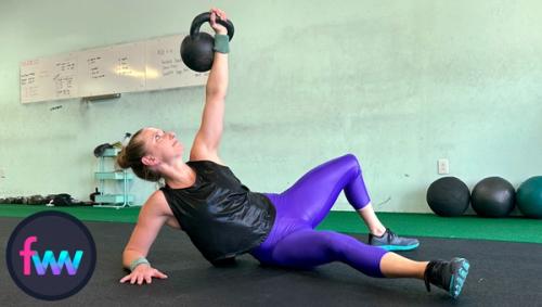 Kindal in the second position of the Turkish get up thrusting the kettlebell up so she's on her forearm.