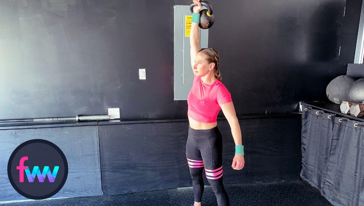 Kindal fully pressing the kettlebell over her head and keeping her balance over her feet.