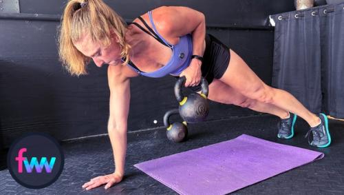 Kindal pulls the kettlebell to the top of the renegade row. Her body is locked out and she is pushing into the ground with her other arm.