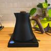 A black modern kettle with a dark wood handle and lid knob — sitting on a black rectangular base.