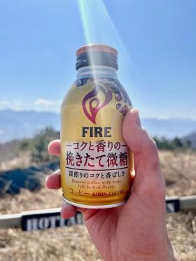 A metal bottle of Kirin Fire held up against the backdrop of the mountains.