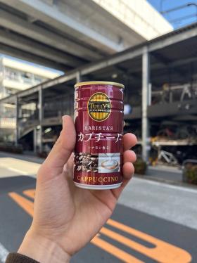 A can of Tully's Ito En coffee being held up against the backdrop of an elevated highway.