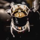 An induction friendly moka pot brewing on a stove.