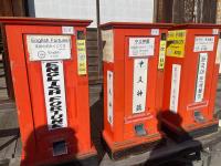 Three red metal boxes with little slots at the bottom