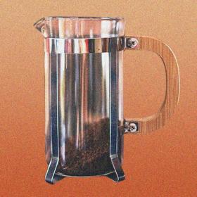 A french press with coffee grounds resting in the bottom, on an orange background.