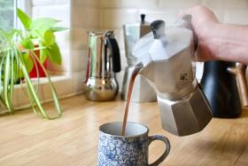 A 6 cup moka express pouring coffee into a mug.