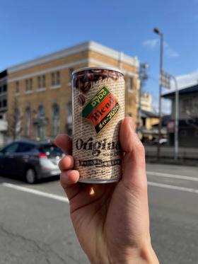 A can of Dydo Blend Original held up against a backdrop of a highway.