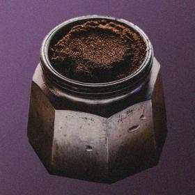 Moka pot bottom chamber with funnel filled with coffee, on a purple background.