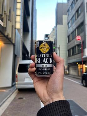 A can of Georgia Coffee Platinum Black against the backdrop of a narrow Tokyo Street.